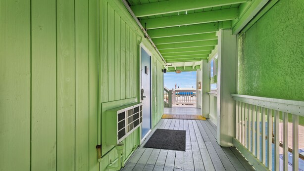A covered wooden walkway with a black mat at the entrance, leading to a beach area. - Oceanfront Inn Suite #6- King Bed (Fort Pierce)
