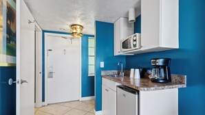 A compact kitchen with white cabinets, a microwave, a coffee maker, and a dishwasher.