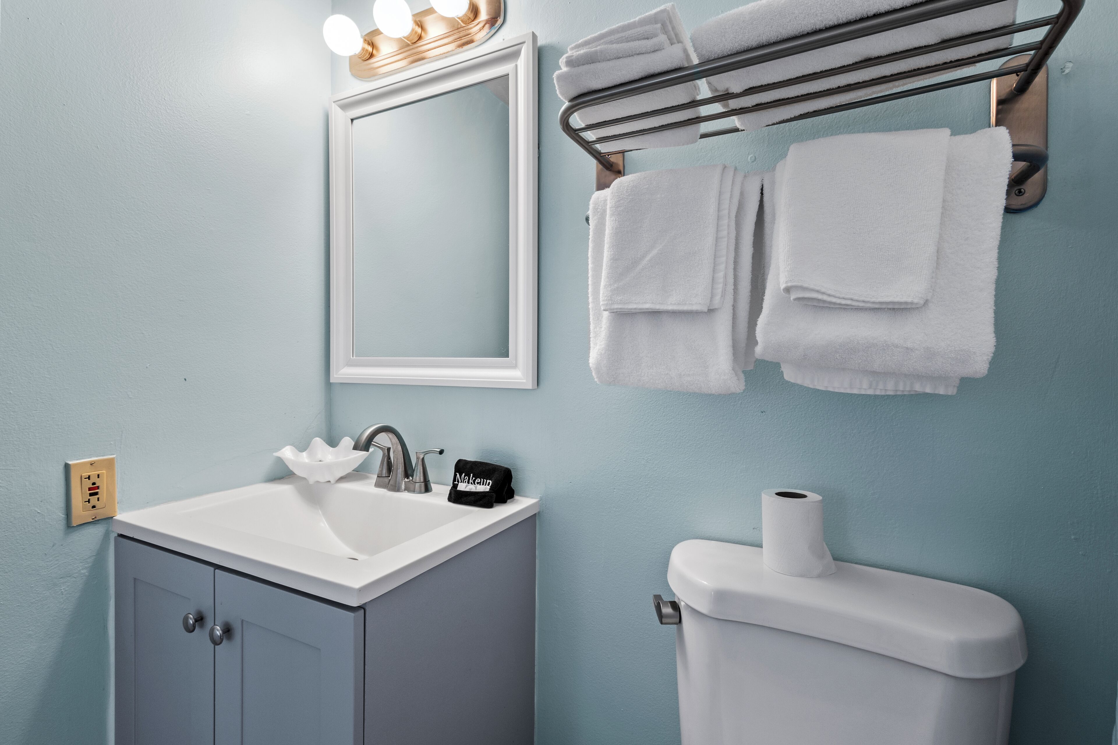 A bathroom with a sink, mirror, towel rack, and toilet.