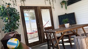 A rustic outdoor seating area with a wooden table and chairs, a volleyball, and hanging plants. - PrivateOakForest RanchFirepit, BBQ&FamilyRetreat (Clermont)