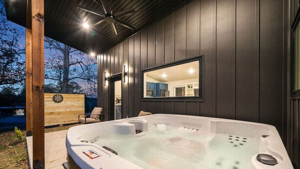 Een hottub met een houten terras, een spiegel en uitzicht op de achtertuin.