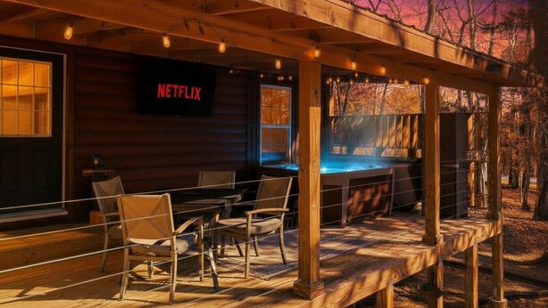 Une cabane en bois dotée d’un porche couvert, de sièges d’extérieur et d’un panneau indiquant la présence de Netflix.
