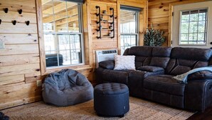 Un intérieur de chalet chaleureux avec un canapé d’angle, un fauteuil poire et un petit pouf.