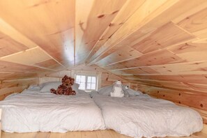 A cozy attic bedroom with a large bed, two pillows, and two stuffed animals. - Tiny Home Escape: Hot Tub, Private Deck & Outdoor TV (Jamestown)