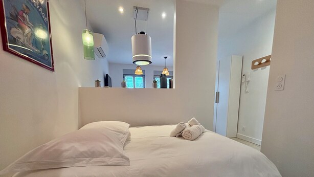 A modern bedroom with a large bed, white bedding, and multiple hanging lights. - CASA BLUM #2 - Studio climatisé, à 2 pas de la gare (Brive-la-Gaillarde)