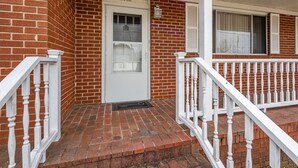 A brick building with a white door and a porch. - Coastal Beaufort Getaway Near Downtown & Beaches (Beaufort)