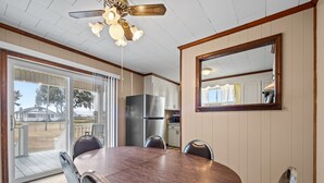 A dining area with a wooden table and chairs, a ceiling fan, and a kitchen in the background. - Coastal Beaufort Getaway Near Downtown & Beaches (Beaufort)
