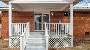 A covered porch with white railings and a brick exterior. - Coastal Beaufort Getaway Near Downtown & Beaches (Beaufort)