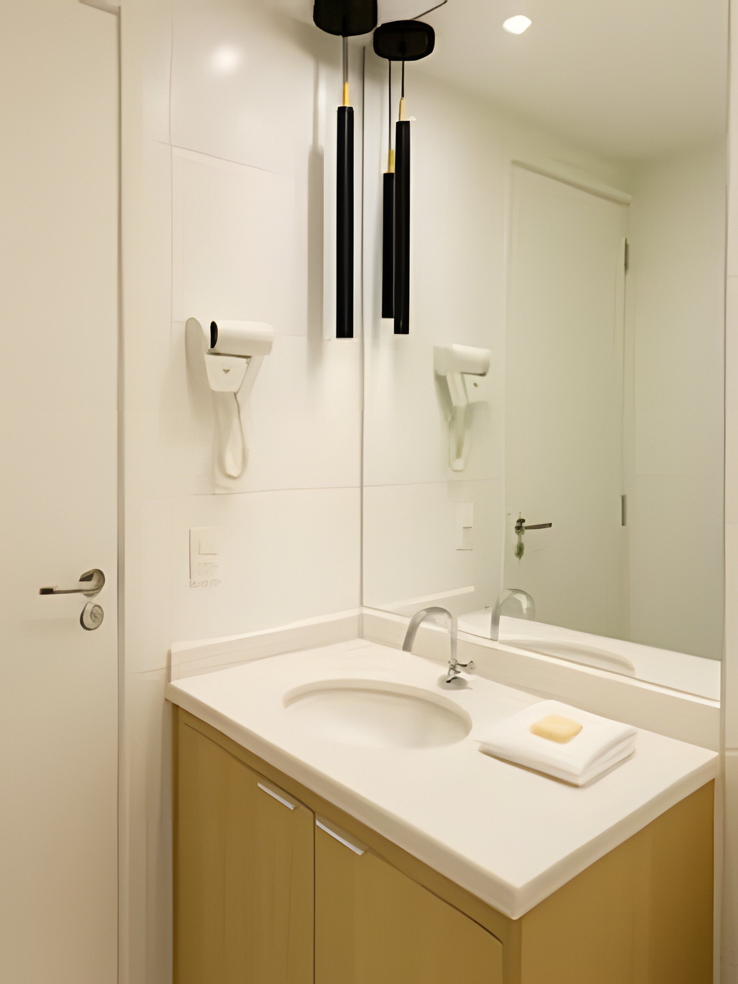 Een moderne badkamer met een witte wastafel, spiegel en twee zwarte handdoekdispensers.