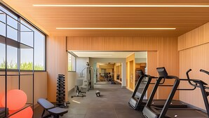 Une salle de sport équipée de tapis de course, de poids et de bancs.