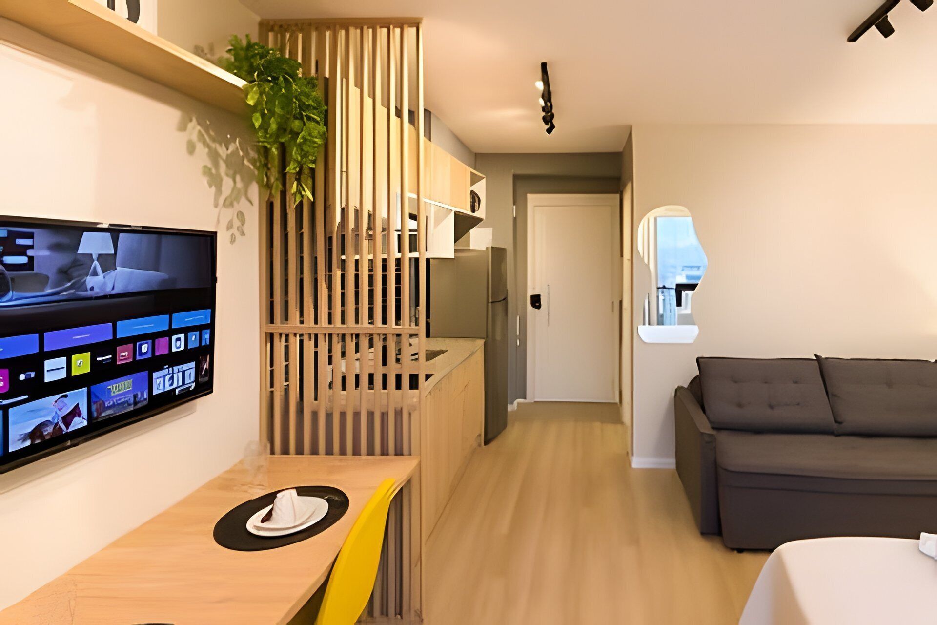 Een moderne woonkamer met een flatscreen-televisie, houten meubels en uitzicht door een raam.