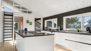 A modern kitchen with a central island, white cabinetry, and a large window providing natural light. - "Månviva" - 250m from the sea by Interhome (Løkken)