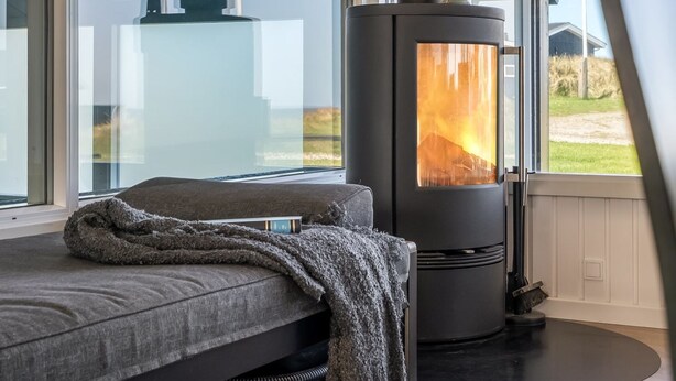 A modern room with a large window, a sofa, and a wood-burning stove. - "Månviva" - 250m from the sea by Interhome (Løkken)