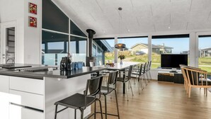 A modern kitchen with a large island, bar stools, and a dining area with a view of the outdoors. - "Månviva" - 250m from the sea by Interhome (Løkken)