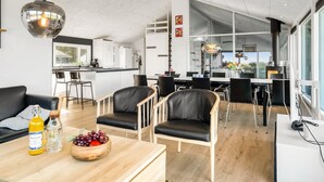 A modern kitchen with white cabinets, a dining area with black chairs, and a large window providing natural light. - "Månviva" - 250m from the sea by Interhome (Løkken)