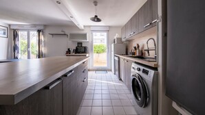 A modern kitchen with a large island, built-in appliances, and a view to the outside. - L'Écrin Toulousain - Piscine partagée et parking (Toulouse)