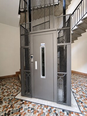 A metallic elevator with a keypad, surrounded by a tiled floor with a geometric pattern. - BIG Smart Goldoni [Duomo-M4 Lin Airport] (Milan)