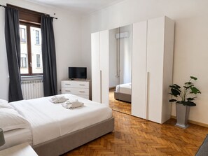 Een hotelkamer met een bed, een dressoir, een televisie, een kledingkast en een potplant.