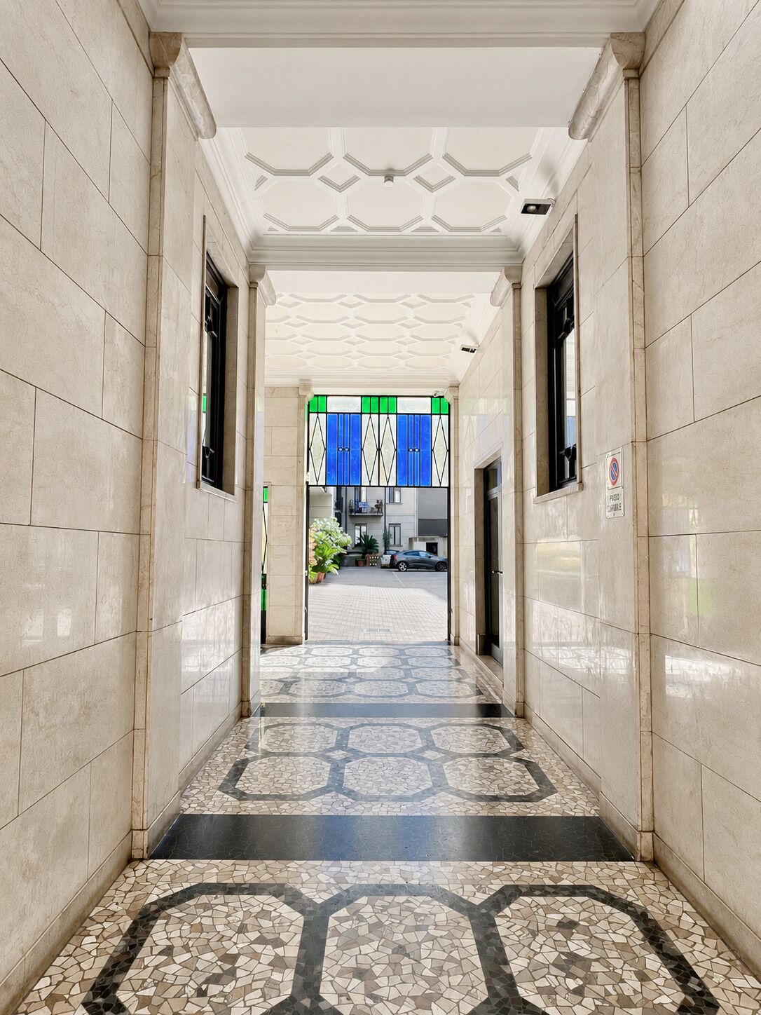 Un pasillo con paredes y suelo de baldosas que conduce a una habitación con ventana.