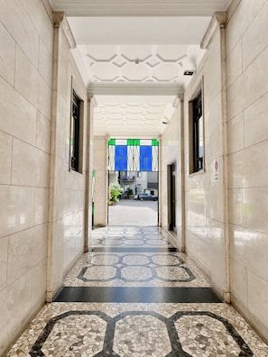 A hallway with tiled walls and floor, leading to a room with a window. - BIG Smart Goldoni [Duomo-M4 Lin Airport] (Milan)