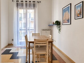 Un comedor con una mesa y sillas, un radiador, una planta y dos cuadros en la pared.