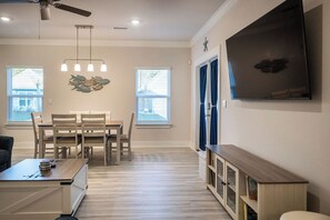 A spacious living room with a dining area, a ceiling fan, and a TV mounted on the wall. - Salty Joe's-WindMark Beach-Pools-Golf Cart-Sleeps 10-InLaw Suite (Port St. Joe)