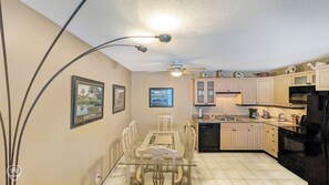 A kitchen with a dining table, chairs, cabinets, a refrigerator, and a ceiling fan. - Purcell Condo – Mountain Escape Near Skiing (Kimberley)
