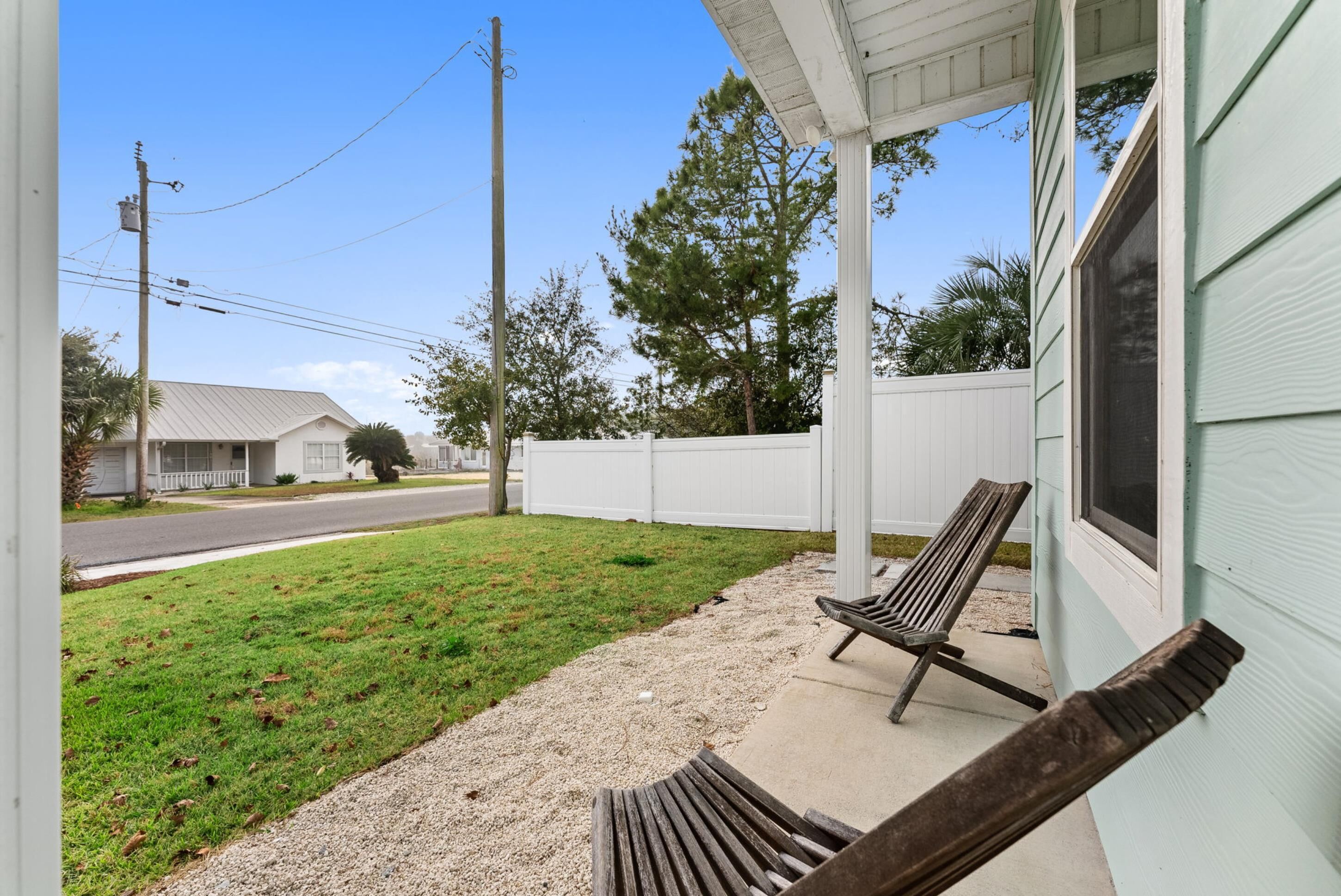 A porch with a bench, a white fence, and a grassy yard.