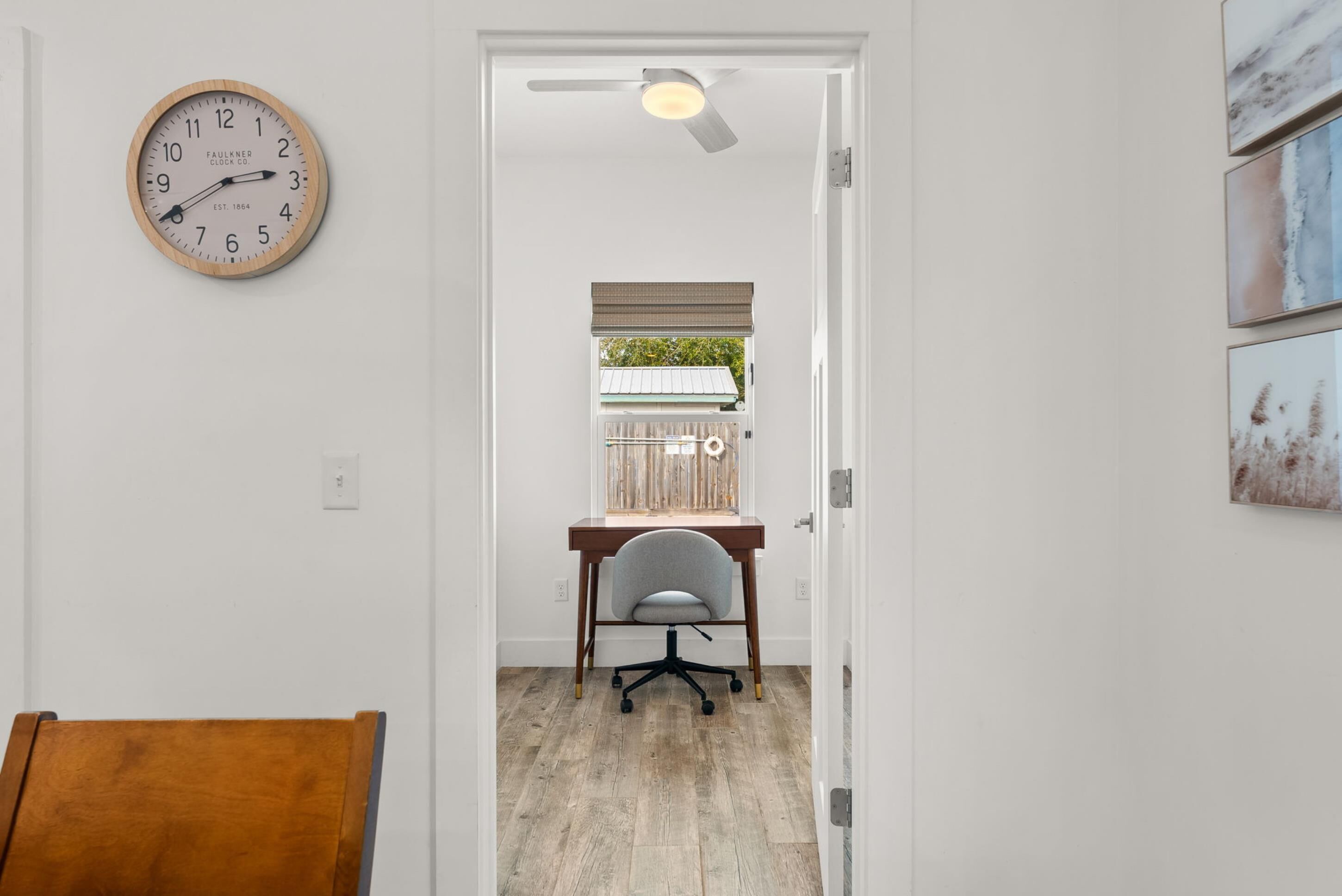 Un pasillo con un escritorio de madera, una silla y un reloj de pared.