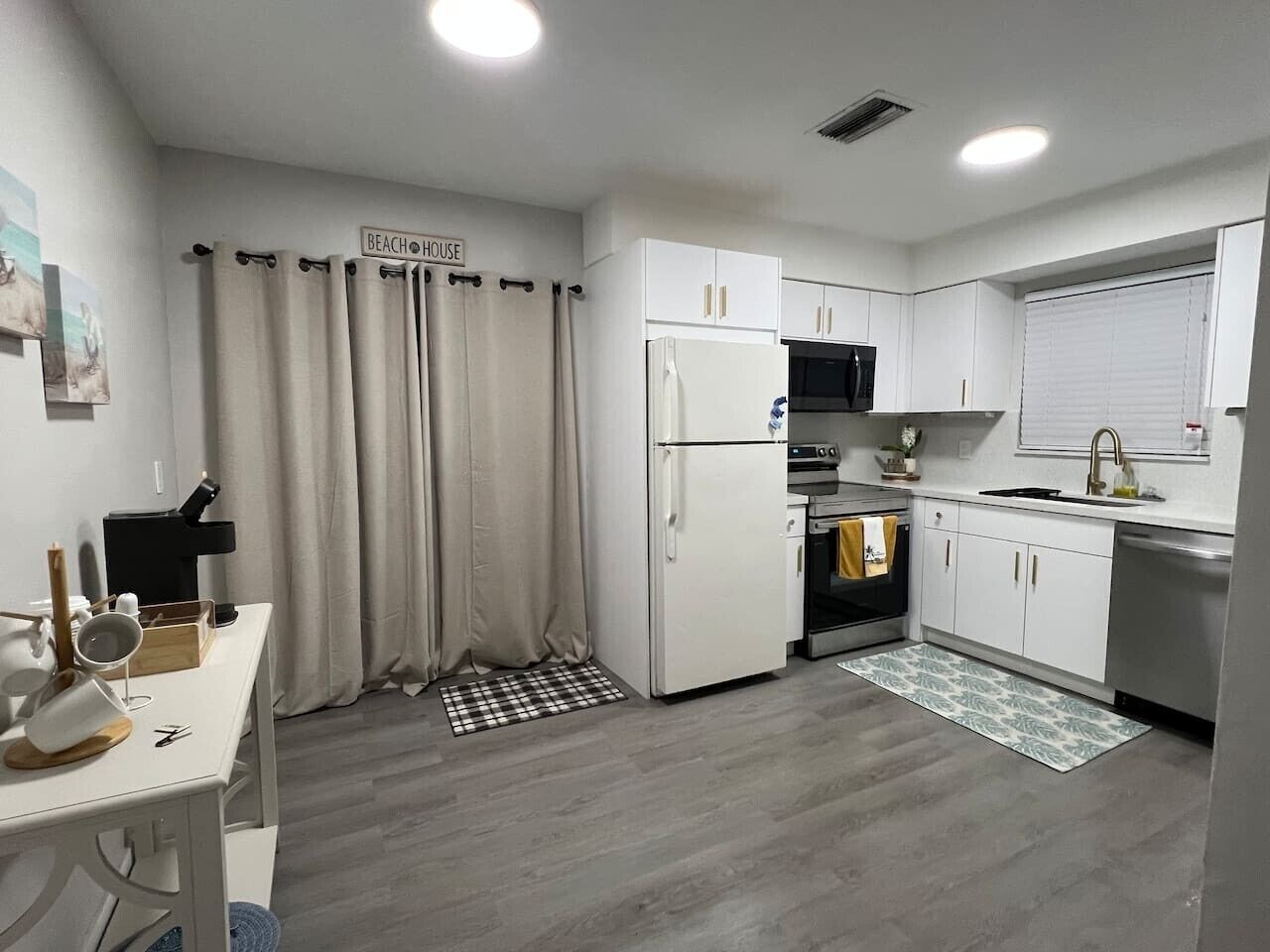 A modern kitchen with white cabinets, a refrigerator, an oven, and a microwave.