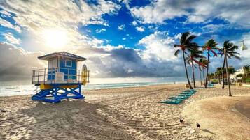 A lifeguard tower on a sandy beach with palm trees and a clear sky.