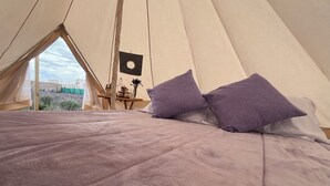 A tent with a bed, pillows, and a small table with a lamp. - Lavender Dream in Glamping Rincón de Lavanda (Texcoco de Mora)