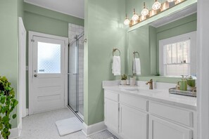 Een badkamer met een douche, een wastafel met spiegel en een handdoekrek.