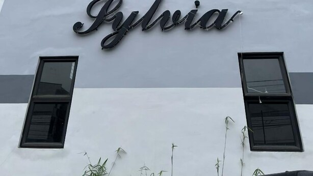 Un bâtiment sur lequel est apposée une enseigne indiquant le nom « Pylvia », écrit dans une police de caractères cursive.