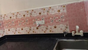 Een keuken met een spoelbak, aanrecht en een muur met decoratieve tegels.