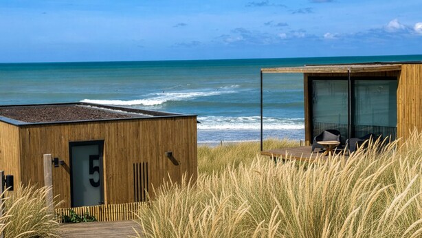 A wooden building with a glass door marked '5', overlooking a beach with waves and a clear sky. - Punta Cantera Suites de Mar (Mar del Plata)