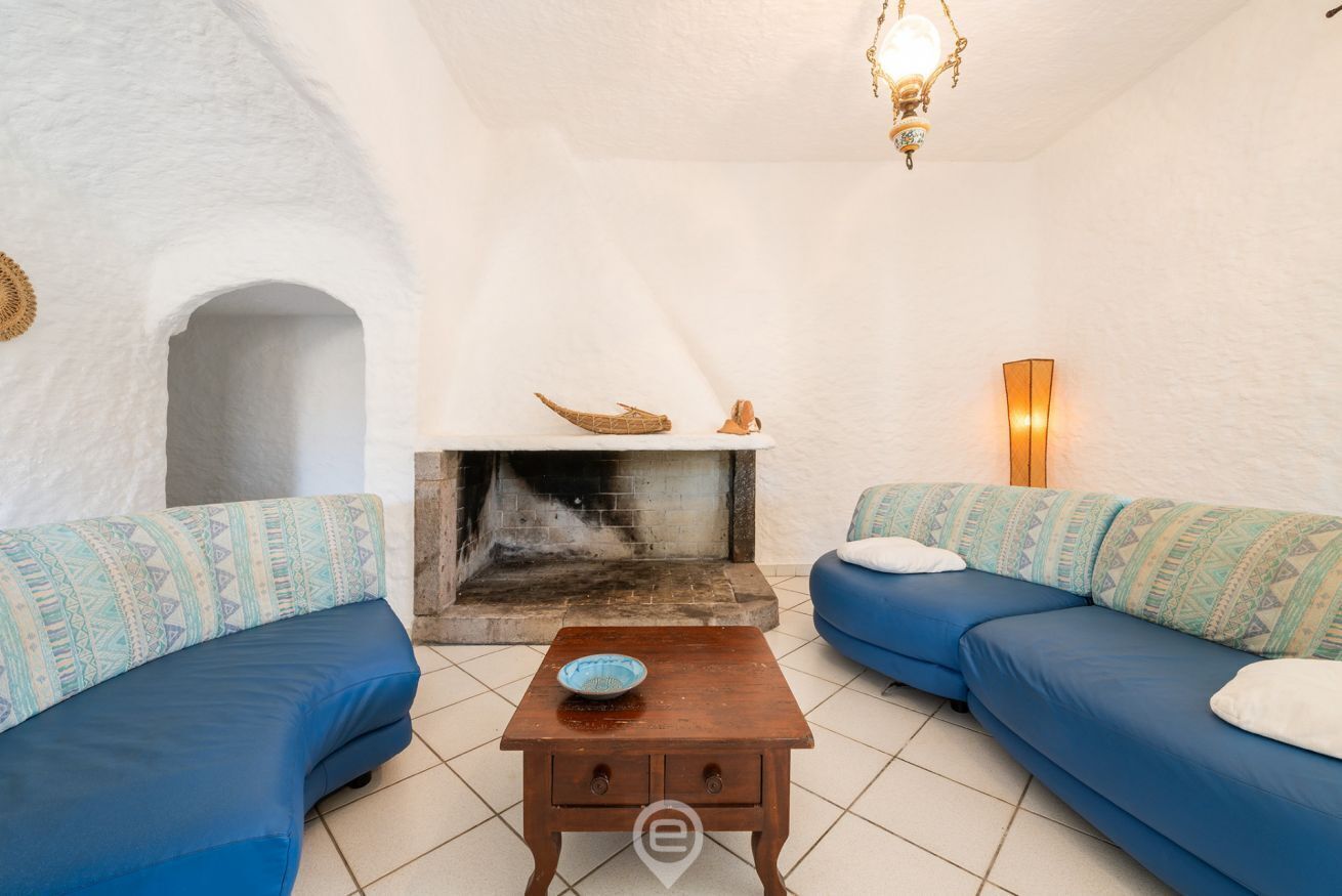 A cozy living room with a fireplace, two blue sofas, and a small wooden table.