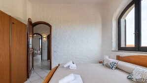 A hotel room with a bed, a wooden wardrobe, a mirror, and a window with a view.