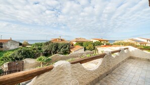 A coastal property with a terrace overlooking the sea, featuring traditional architecture and a stone wall.