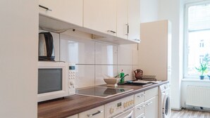 A kitchen with white cabinets, a microwave, a kettle, and a washing machine. - Modern Long-Stay 3-Room Apt near Wiener Stadthalle (Vienna)