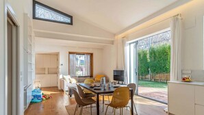 A modern interior with a dining area, kitchen, and large windows.