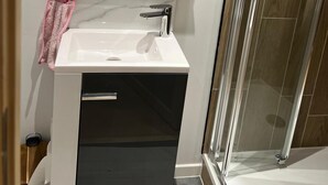 Ein Badezimmer mit einem weißen Waschbecken, einem Spiegel und einer Duschkabine aus Glas.