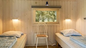 Una habitación pequeña y acogedora con dos camas, una silla y una ventana.