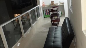 Un pasillo estrecho con un banco de cuero negro, una mesa de comedor con sillas y una cocina visible a través de un tabique de vidrio.