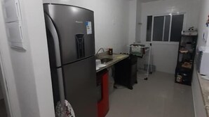 Una cocina compacta con refrigerador, lavamanos y ventana.