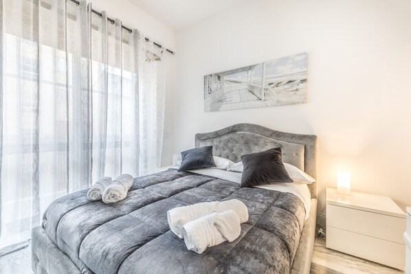 A modern bedroom with a large bed, a headboard, and a bedside table with a lamp. - Asinari Retreat [San Marzano] (Roma)