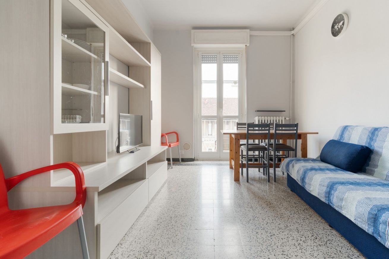 A compact room with a bed, a desk with a chair, a TV, and a window.