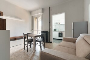 A modern living room with a sofa, a dining table with chairs, a kitchen area with cabinets and appliances, and a radiator. - GuestHost - A comfortable and welcoming 45 square meters apartment, perfect for four people, located on the fourth floor of a building without an elevator.The property is located in the Navigli district, one of Milan's liveliest areas: guests can enjoy r (Milan)
