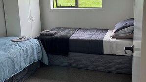 A small, single-bed room with a window, a wardrobe, and a carpeted floor.