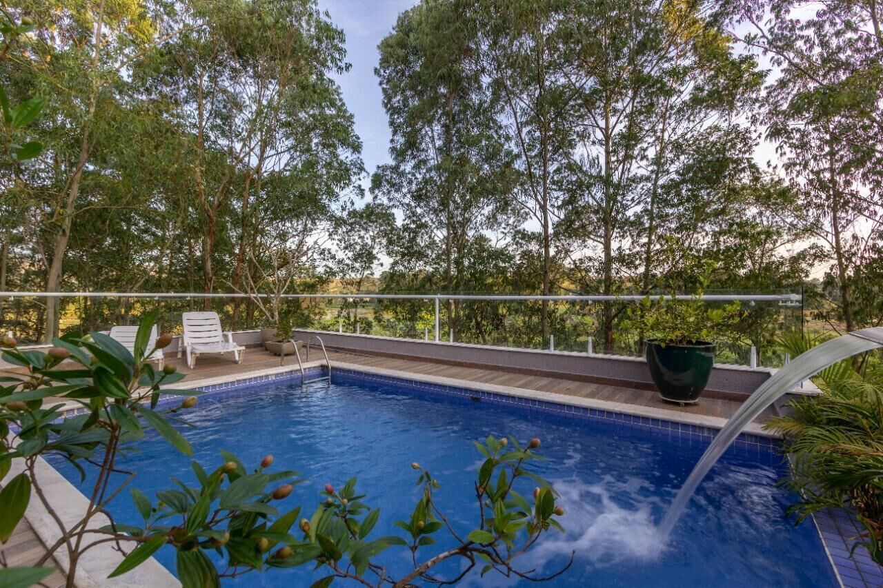 A swimming pool with a waterfall feature, surrounded by lush greenery and trees.